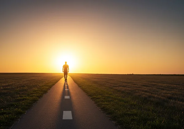 Person walking on a clear path towards a brighter horizon.